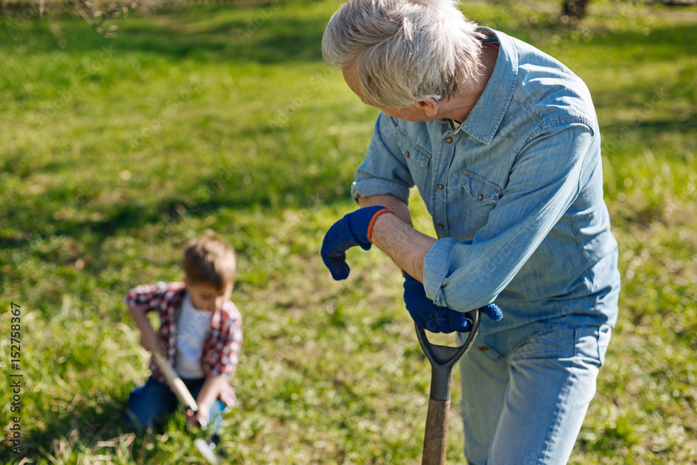 Grandfather looking at child scooping ground Grandfather looking at child scooping ground