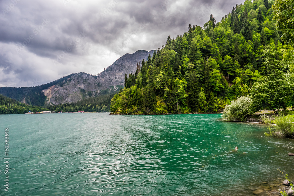 The emerald green lake framed by the forest and mountains in the gloomy rainy weather The emerald green lake framed by the forest and mountains in the gloomy rainy weather