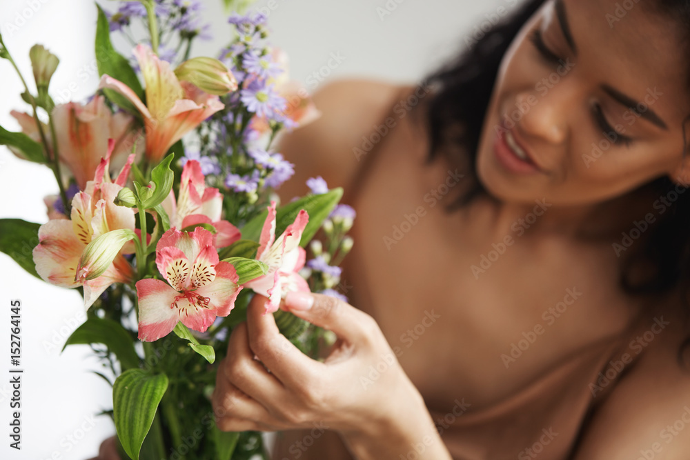 Beautiful african female florist making bouquet of flowers preparing to sell them. Focus on alstroemerias. Young entrepreneur.