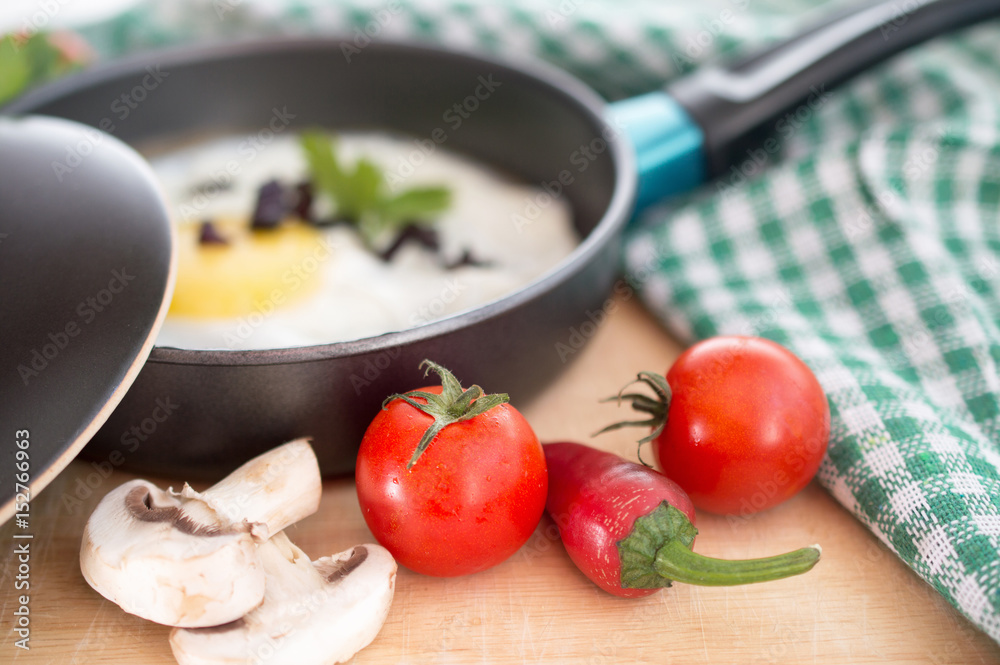 Fresh tomatoes mushrooms and peppers next to an omelet frying pa Fresh tomatoes mushrooms and peppers next to an omelet frying pa