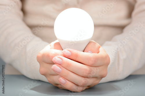 Female hands holding a glowing led bulb