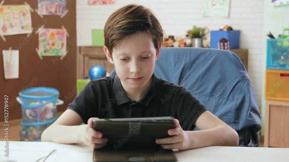 Cute little boy playing computer game using digital tablet Cute little boy playing computer game using digital tablet