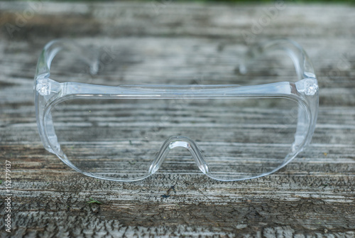 protective transparent plastic glasses on a wooden backgroun photo