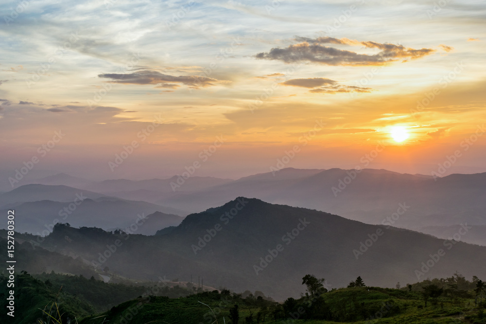 Fototapeta premium Beautiful landscape nature on mountain with sun cloud fog and bright colors of sky and sunlight during sunset in winter at view point Phu Chi Fa Forest Park in Chiang Rai Province, Thailand