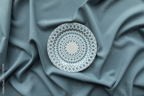 Abstract textile fabric folds and drapes in blue grey colour and ceramic porcelain geometry pattern plate © Полина Власова