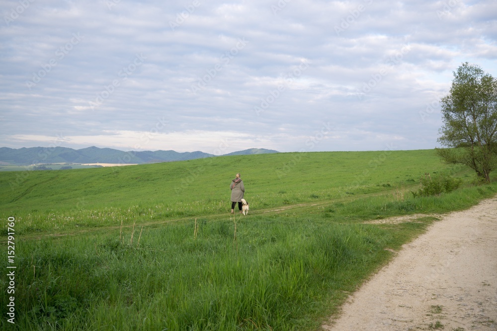 Woman walking a  dog on meadow. Slovakia