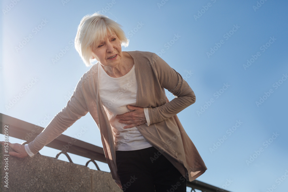 Fototapeta premium Old woman feeling stomachache outside