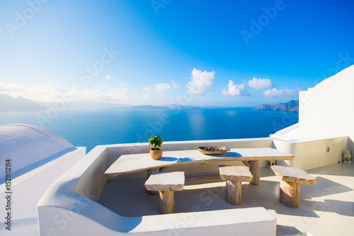 A pot with flower and a plate on a wooden table with ocean background, Santorini, Greece © gatsi