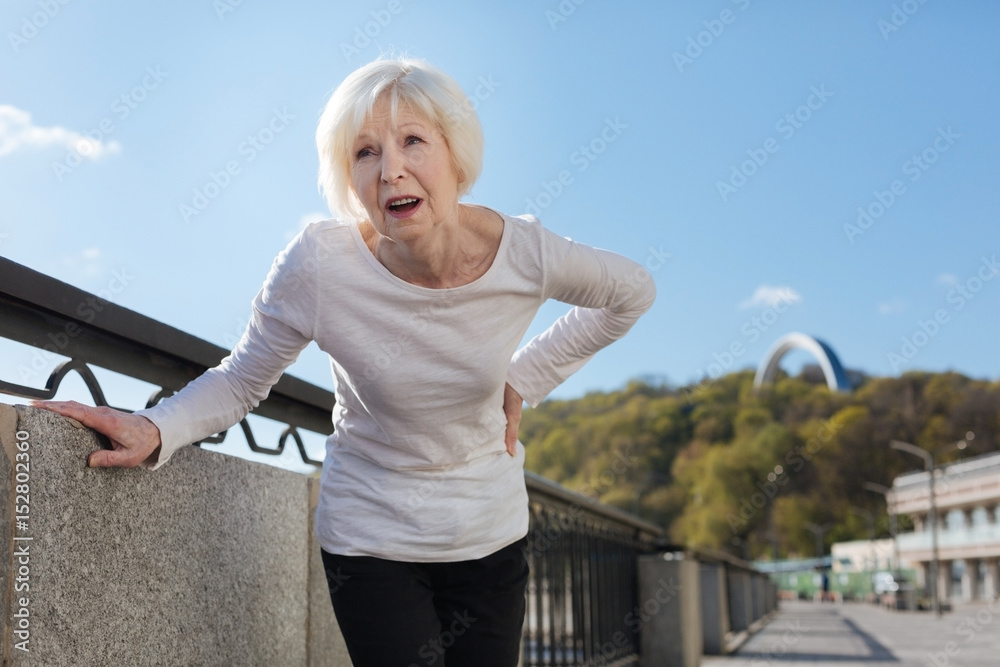 Senior woman feeling backache on the open air