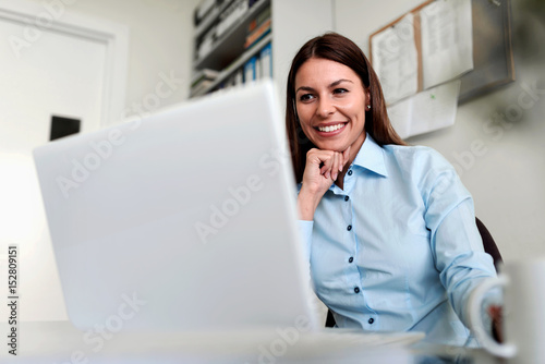 Smiling businesswoman in office working on laptop computer