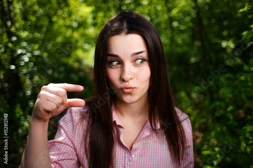 Portrait of mocking or extremely surprised  of something small woman, showing small thing in a gesture photo