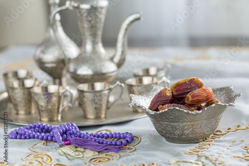 Dates with zam zam water cups background with purple rosary on white table cloth