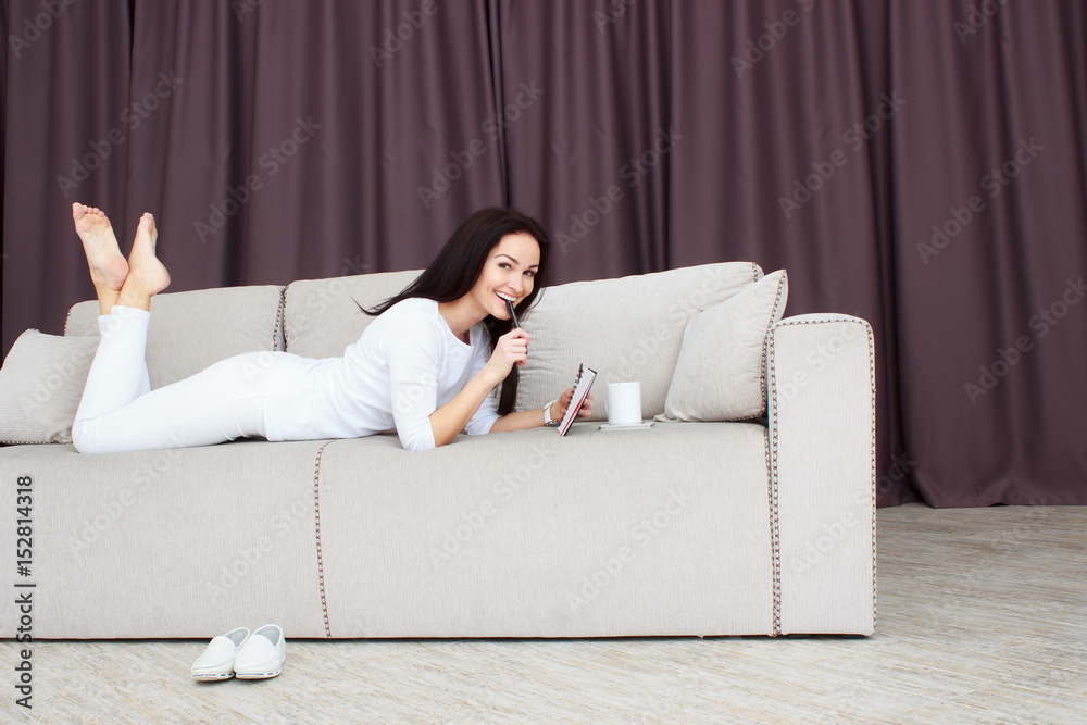 Portrait of beautiful young woman lying on sofa at home with cup of tea Portrait of beautiful young woman lying on sofa at home with cup of tea