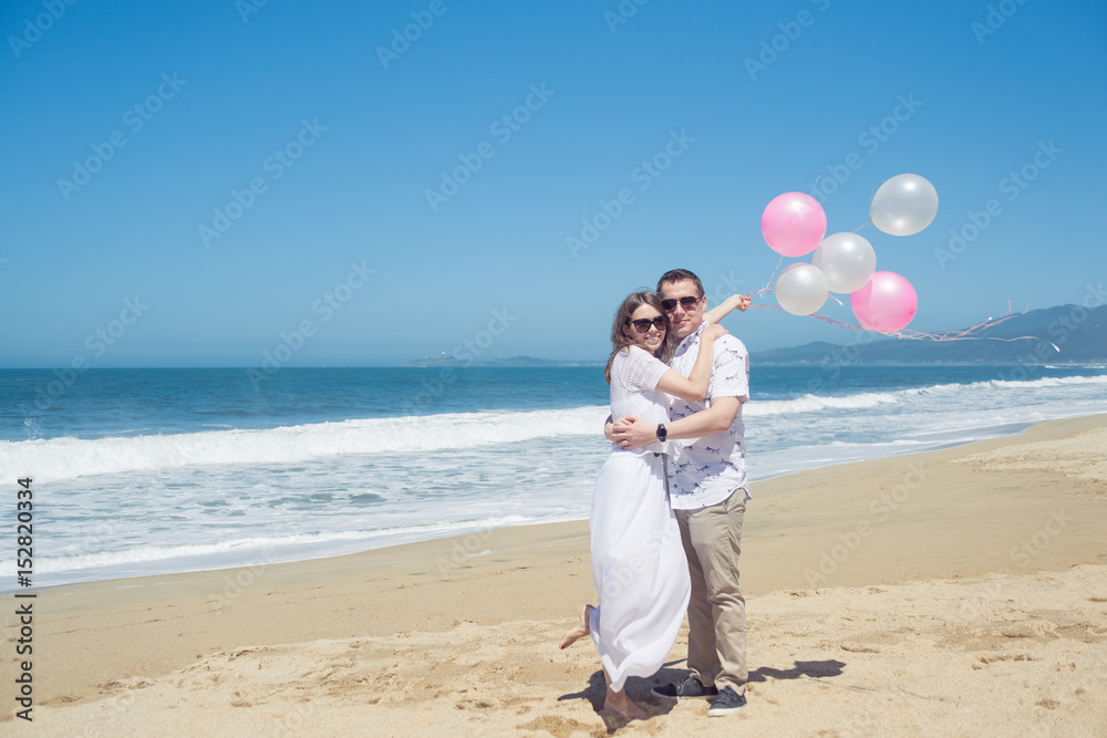Young hugging romantic couple with balloons on the beach Young hugging romantic couple with balloons on the beach