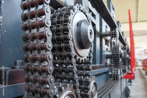 Triple strand roller chain going around three sprockets on industrial machine photo