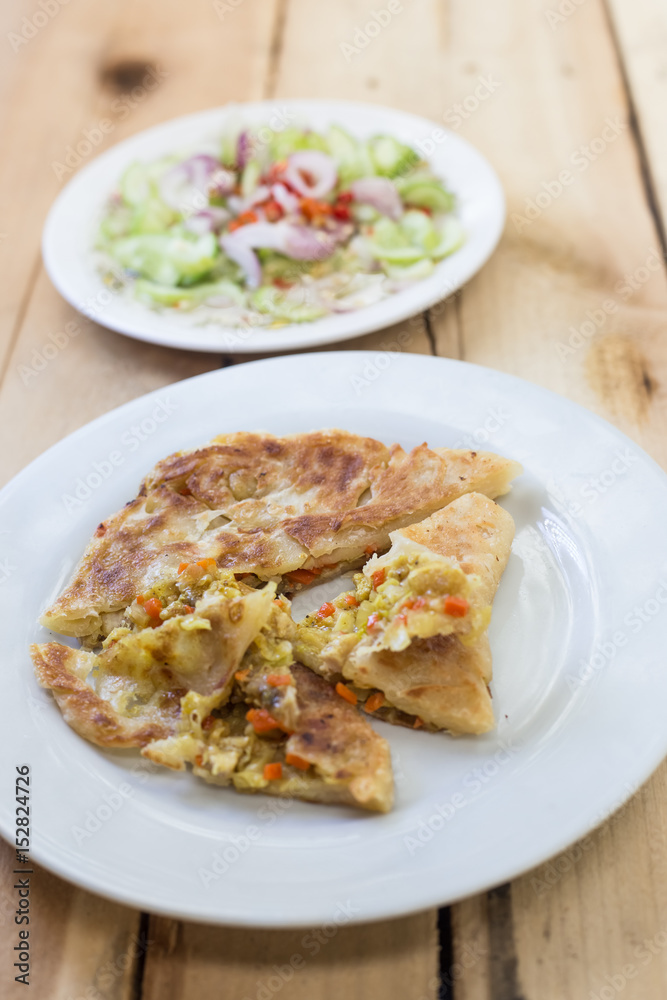 Roti Parata or Roti canai with curry sauce on wooden background.