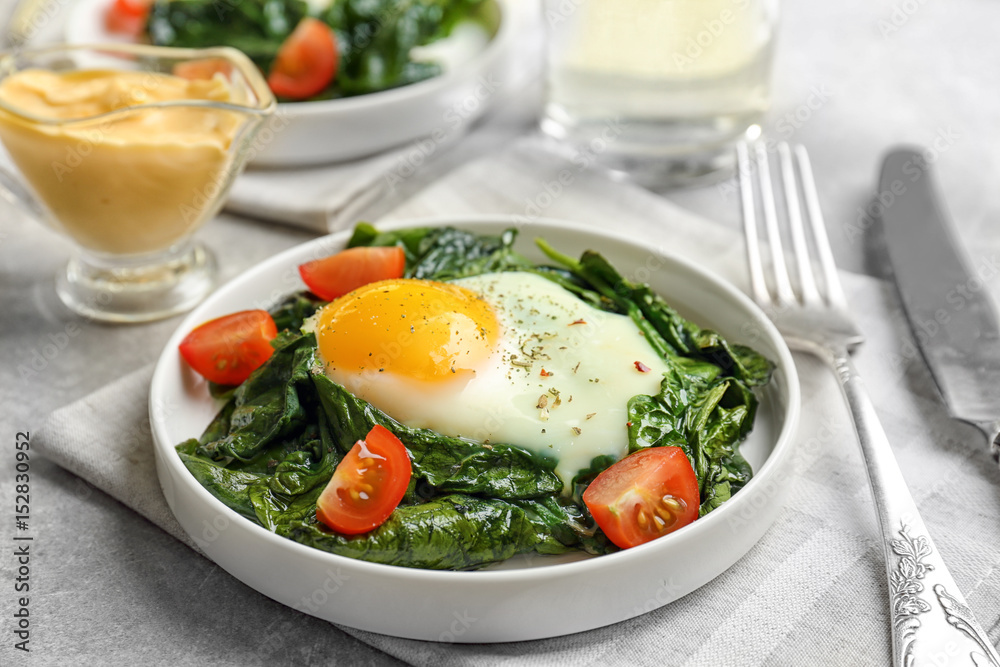 Delicious eggs Florentine with tomatoes on kitchen table Delicious eggs Florentine with tomatoes on kitchen table