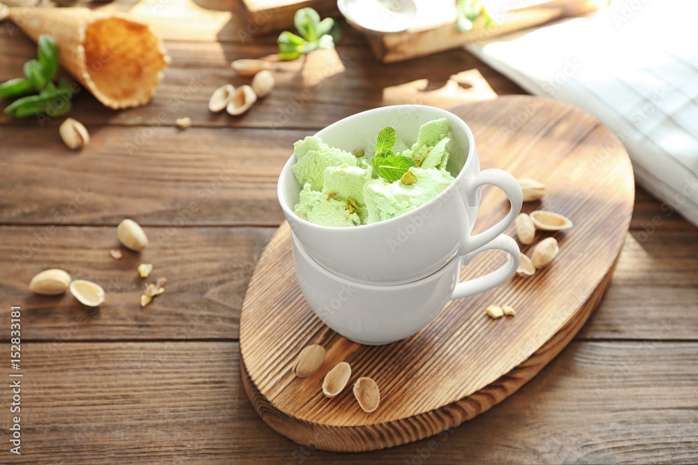 Cups with delicious pistachio ice cream on wooden board Cups with delicious pistachio ice cream on wooden board