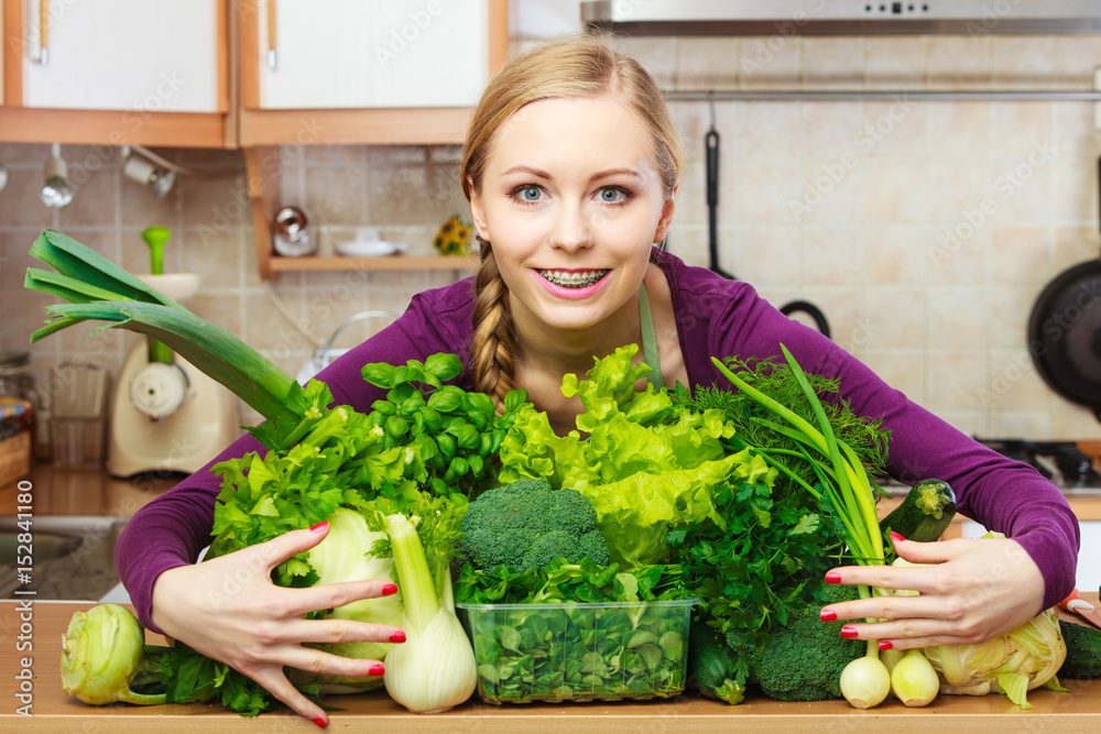 Smiling woman in kitchen with green vegetables Smiling woman in kitchen with green vegetables