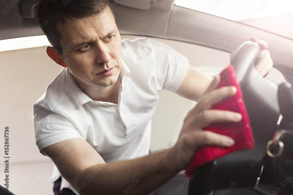 Handsome man polishing steering wheel Handsome man polishing steering wheel
