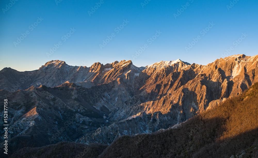 Apuane alpi snowy mountains and marble quarry at sunset in winter. Carrara, Tuscany, Italy.