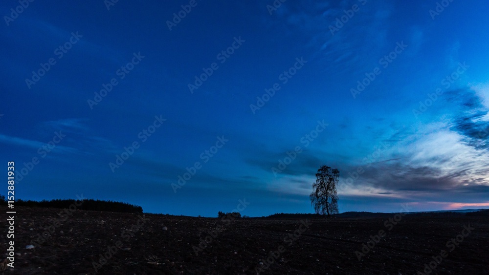 Beautiful colorful sunset sky over plowed field in springtime