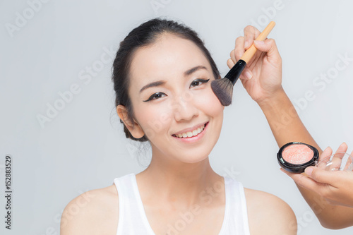 Asian young beauty woman happy with make up artist applied brush on her cheek