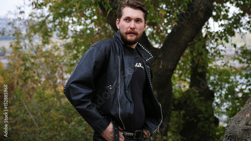 Bearded man in black leather jackets in a forest