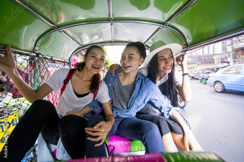 Three asian girls are taking Tuktuk to travel around Chinatown, Thailand