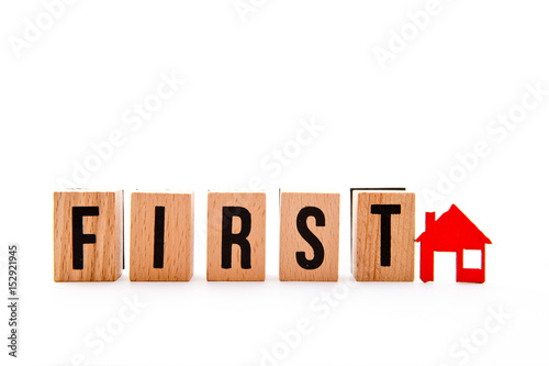 First Home - wooden block letters and red home icon on white background 