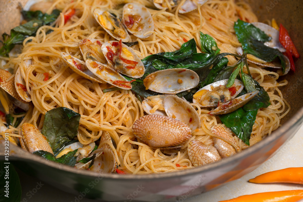 Stir fried Clams and Spaghetti with chili paste in the pan on table in the kitchen / Still life image and Selective focus . Stir fried Clams and Spaghetti with chili paste in the pan on table in the kitchen / Still life image and Selective focus .