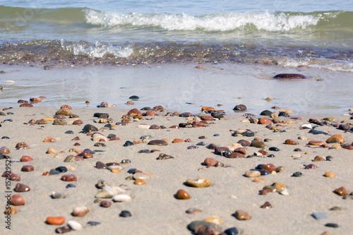 Small rocks scattered on beach sand close up.