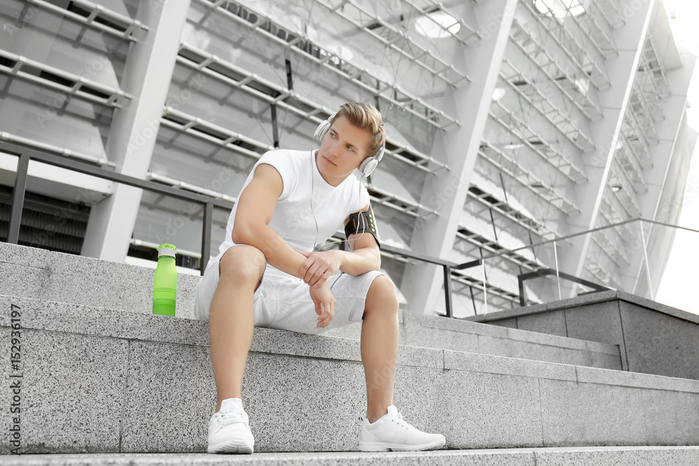Young man with headphones sitting on  stairs