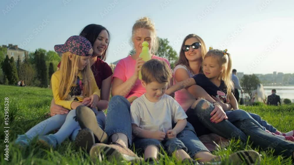 Happy Girls and kids plaing with puppy. Family seatting in park Warm sunny day Happy Girls and kids plaing with puppy. Family seatting in park Warm sunny day