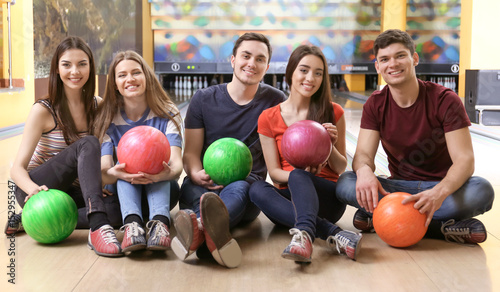 Friends sitting on floor in bowling club