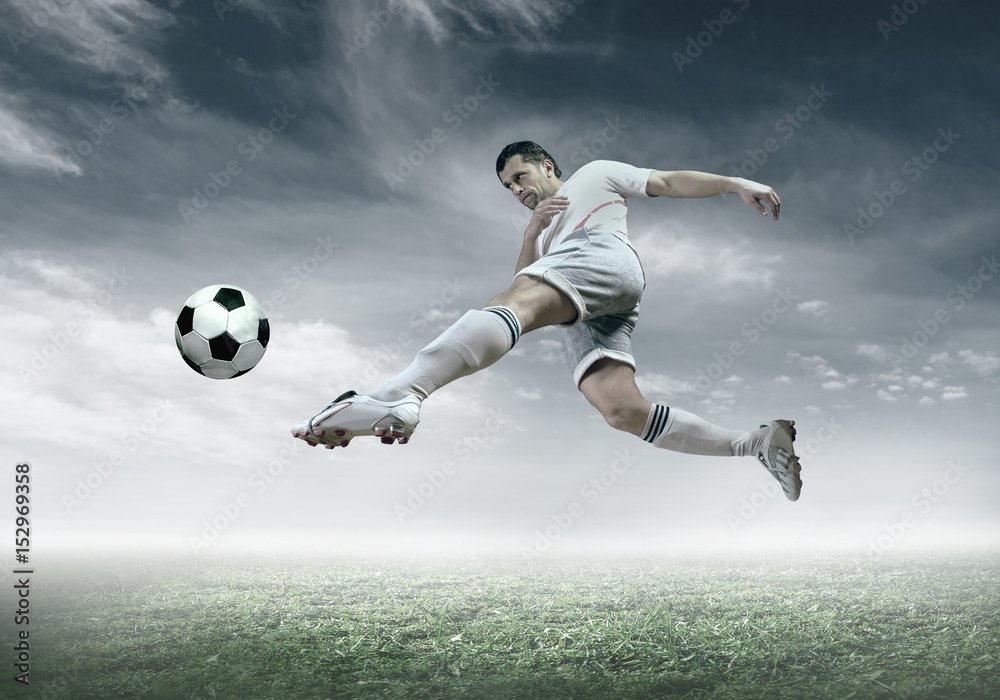 Football player with ball in action under sky with clouds Football player with ball in action under sky with clouds