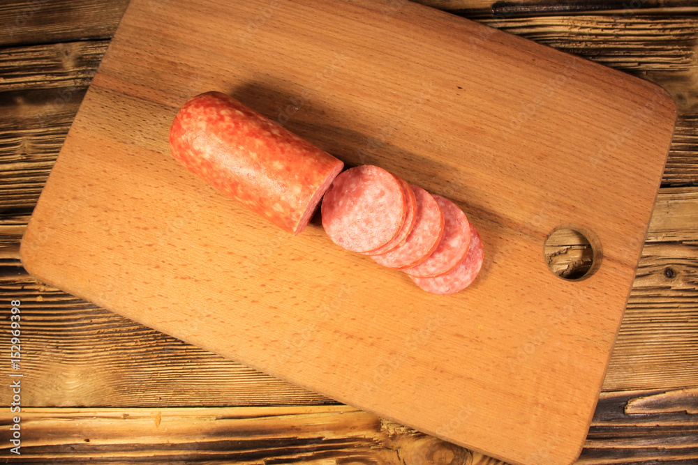 Sausage sliced on cutting board on wooden table Sausage sliced on cutting board on wooden table