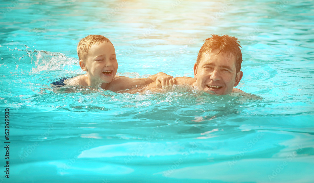 Father and son funny in  water pool under sun light at summer day