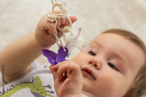 baby is holding pacifier clip for nipple photo