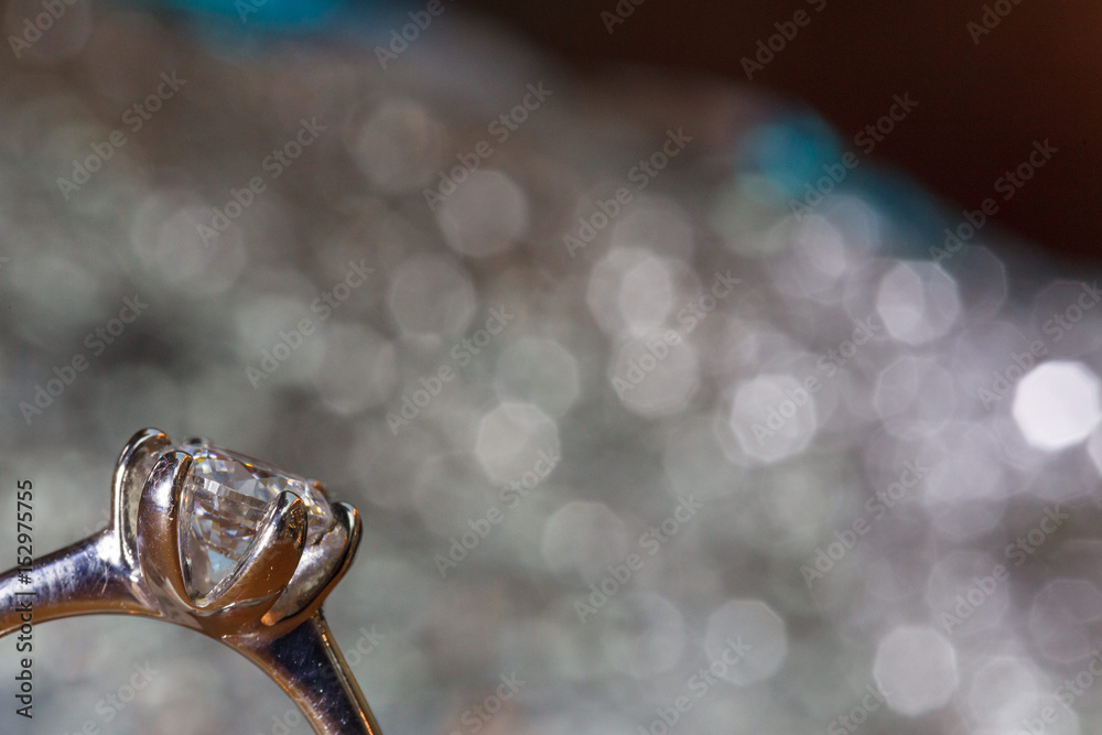 Solitaire diamond ring on silver sparkle background