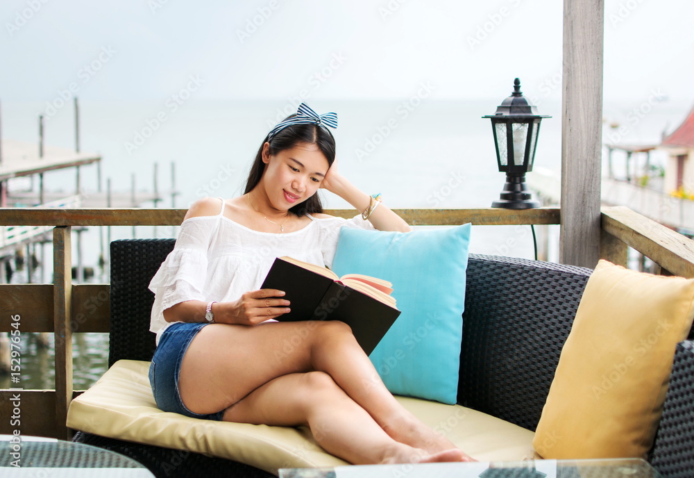 Girl reading book on the balcony with seaside view