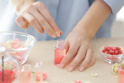 Woman making natural perfume with rose petals  closeup