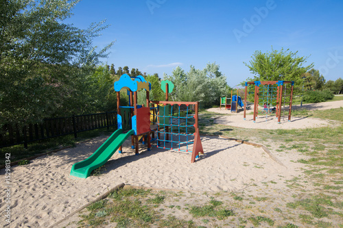 Wallpaper Mural plastic two swing sets on earth sand ground in playground with slide in public Park Valdebebas in Madrid city, Spain Europe 
 Torontodigital.ca