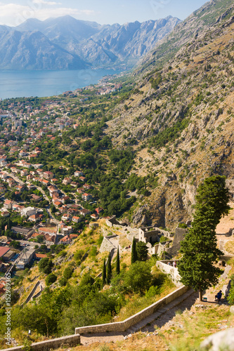 Looking over the Bay of Kotor in Montenegro with view of mountains, boats and old houses with red tile roofs, fortress