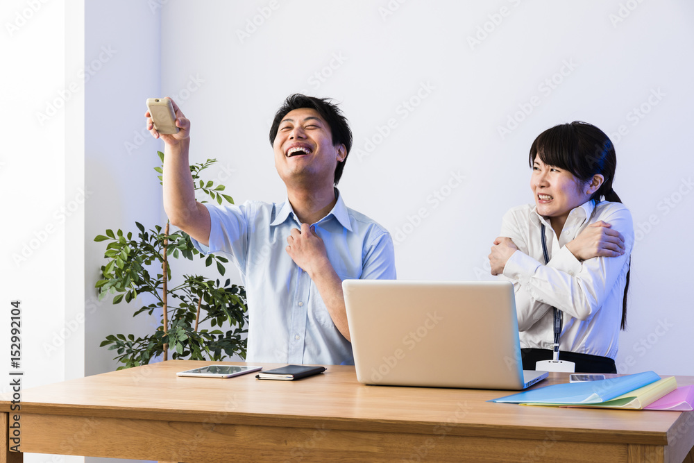 Obraz premium クーラーで涼むビジネスマンと凍えるビジネスウーマン