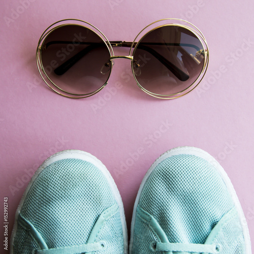 Sunglasses next to green sneakers on a bright background