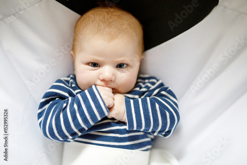 Cute adorable two months baby sucking fist. photo