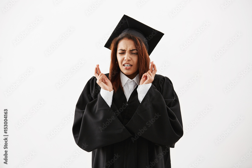 African female graduate in black mantle praying over white background. Copy space. African female graduate in black mantle praying over white background. Copy space.