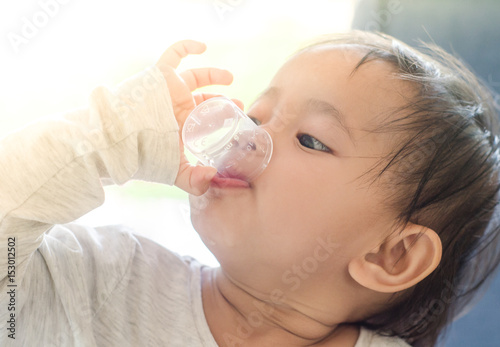 Asian little girl takes medicine syrup by herself