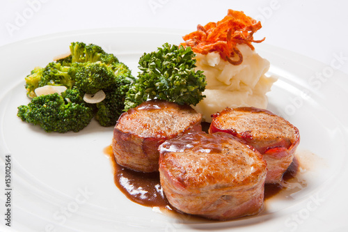 Pork medallions wrapped in bacon, with potatoes and broccoli photo